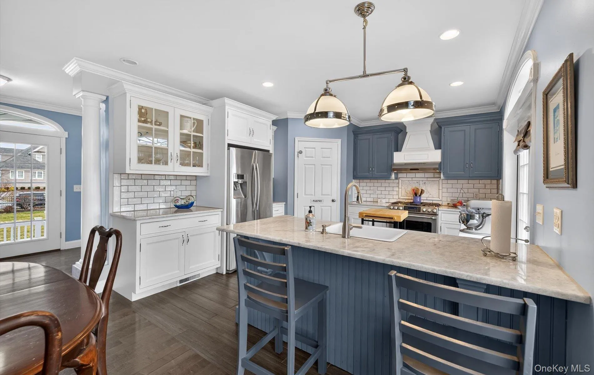 Kitchen with wine cooler, light stone counters, tasteful backsplash, glass insert cabinets, and stainless steel stove Kitchen with wine cooler, light stone counters, tasteful backsplash, glass insert cabinets, and stainless steel stove
