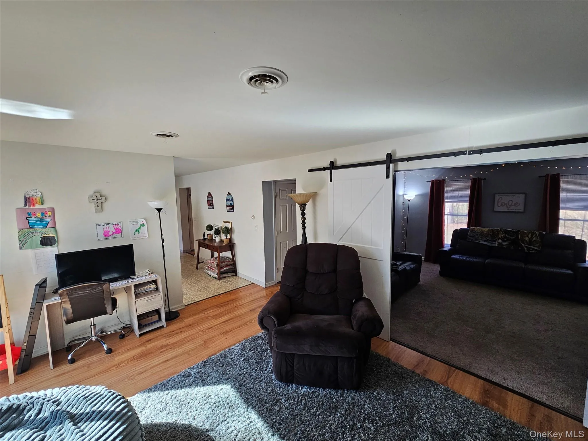 Family with a barn door to living room, light wood finished floors, and a desk Family with a barn door to living room, light wood finished floors, and a desk