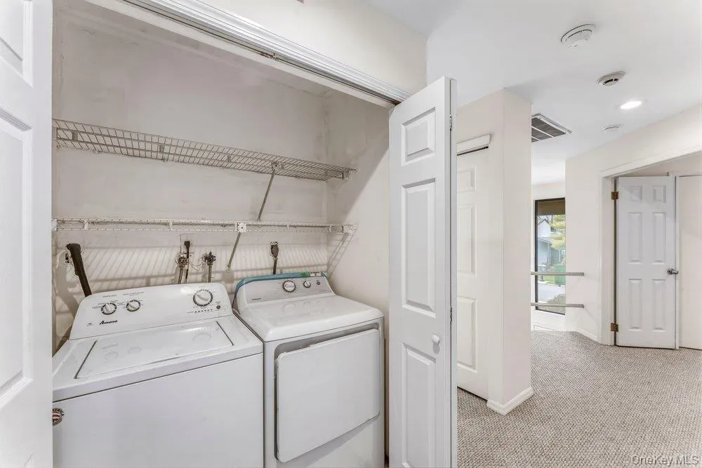 Laundry area featuring light colored carpet and washing machine and dryer Laundry area featuring light colored carpet and washing machine and dryer
