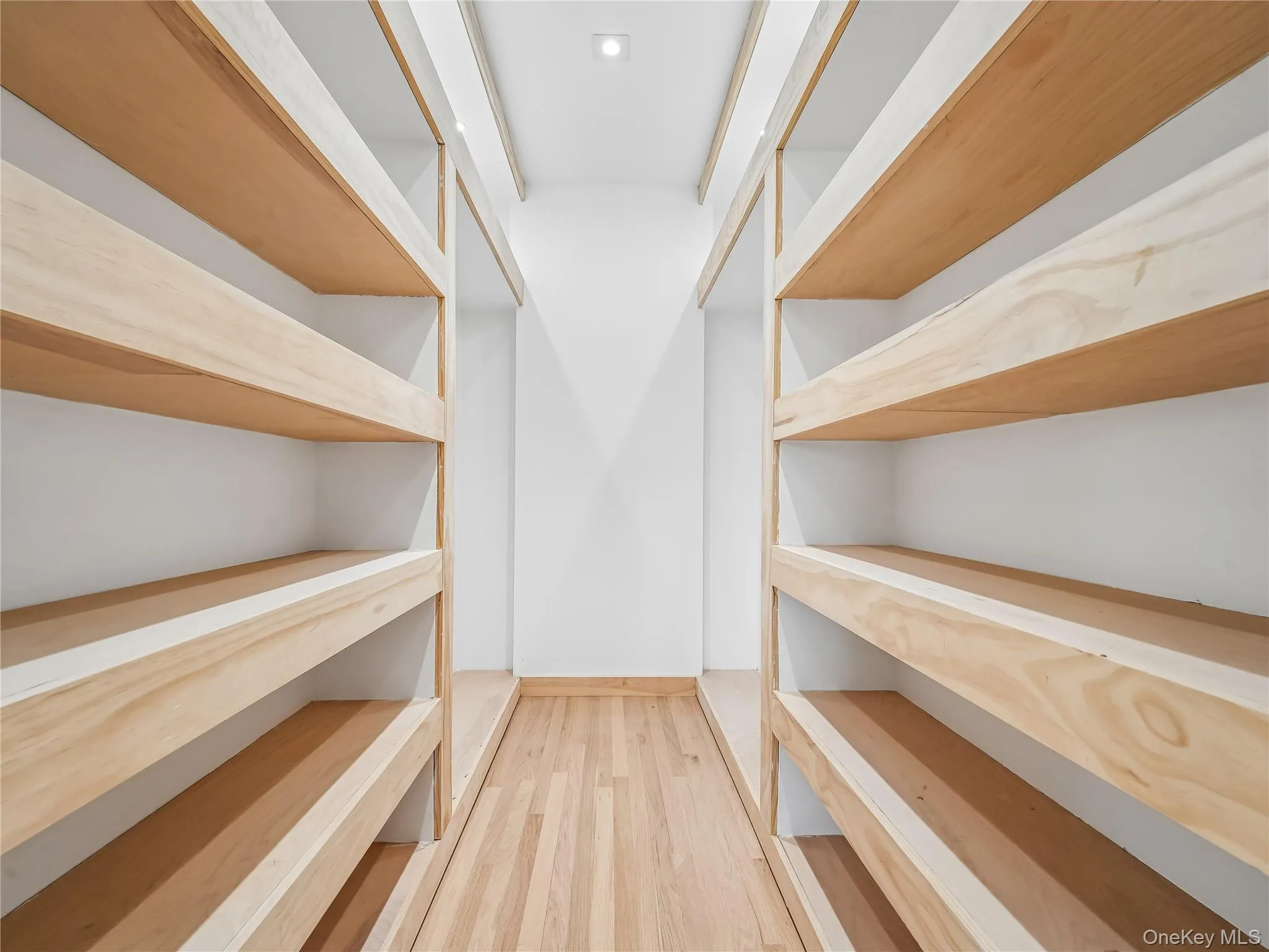 Designer his and hers walk-in closet with wooden shelving and custom lighting. Designer his and hers walk-in closet with wooden shelving and custom lighting.