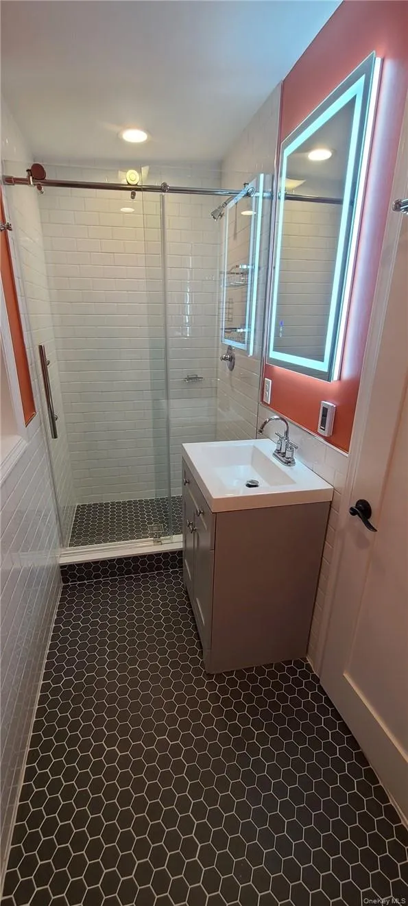 Bathroom featuring walk in shower, oversized vanity, and heated tile floors Bathroom featuring walk in shower, oversized vanity, and heated tile floors