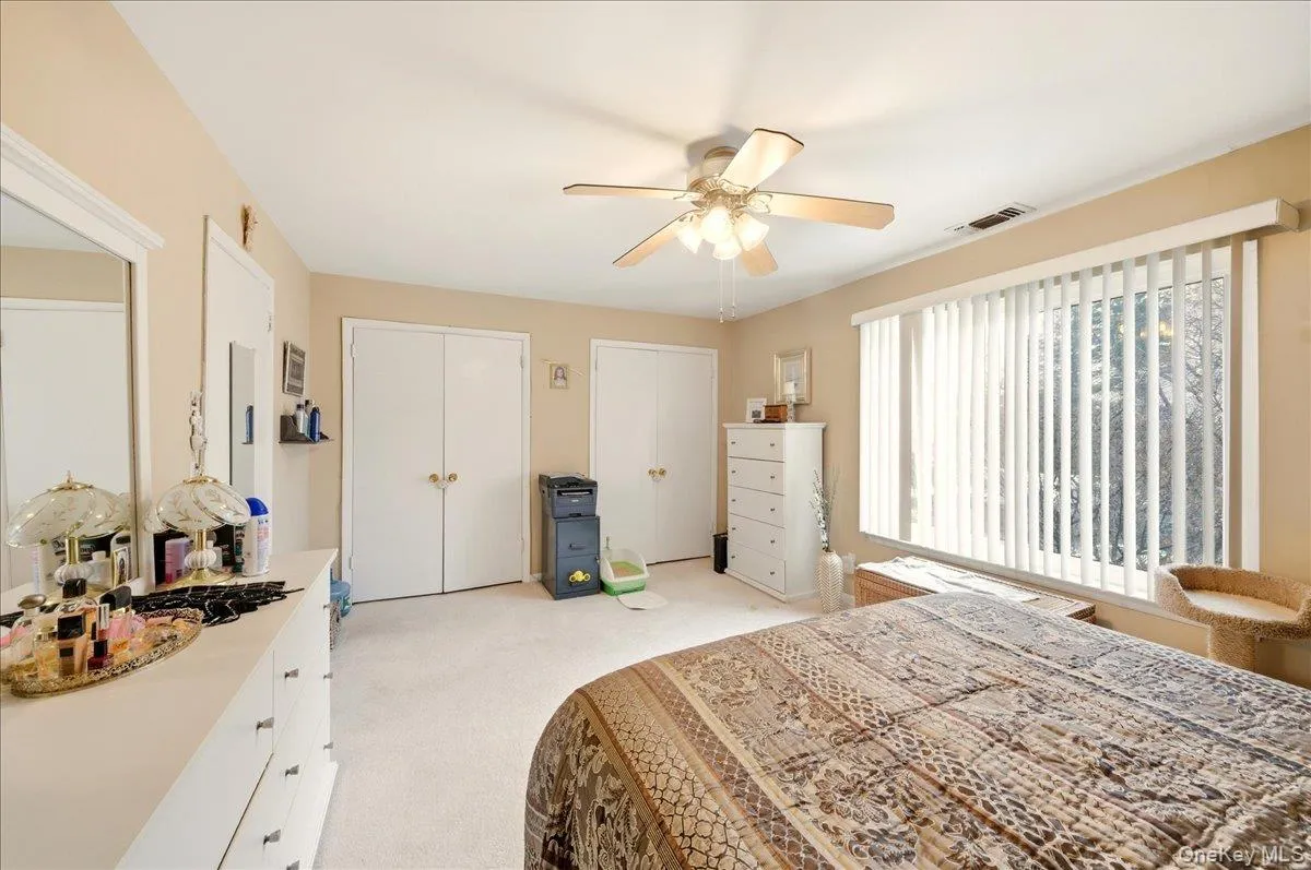 Bedroom with two closets, light colored carpet, and ceiling fan Bedroom with two closets, light colored carpet, and ceiling fan