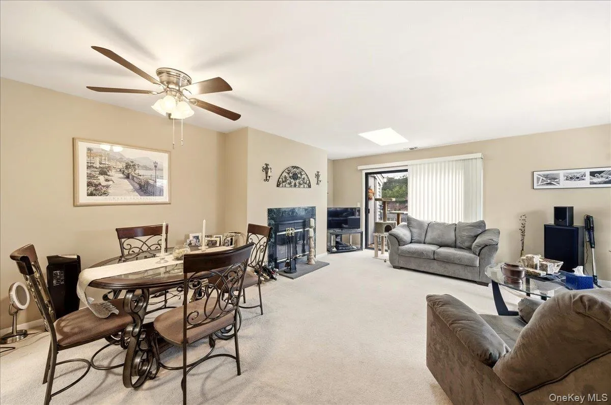 Carpeted living room featuring a glass covered fireplace and a ceiling fan Carpeted living room featuring a glass covered fireplace and a ceiling fan