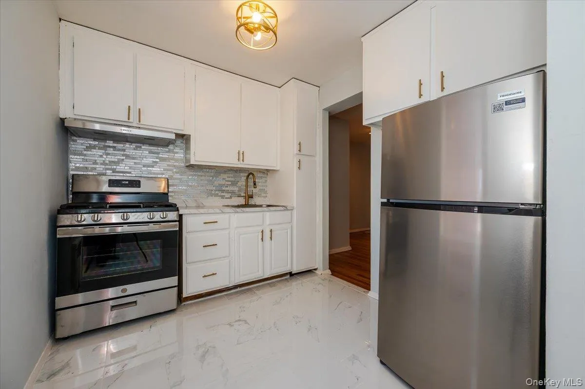 Kitchen features new stainless steel appliances, rangehood, decorative tiled backsplash, tiled flooring, light fixture and countertops. Kitchen features new stainless steel appliances, rangehood, decorative tiled backsplash, tiled flooring, light fixture and countertops.