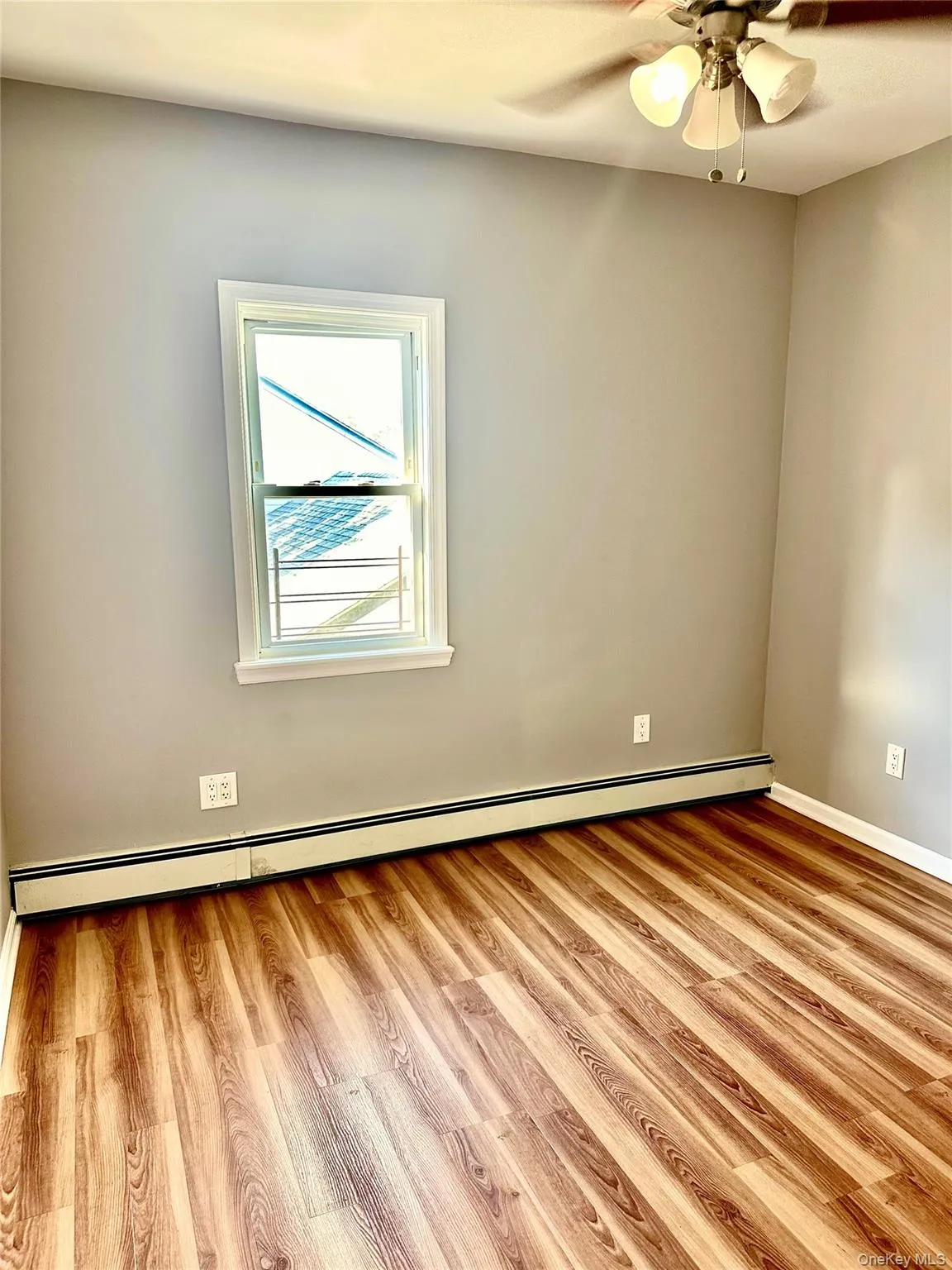 Spare room featuring a baseboard heating unit, light wood-style flooring, and ceiling fan Spare room featuring a baseboard heating unit, light wood-style flooring, and ceiling fan