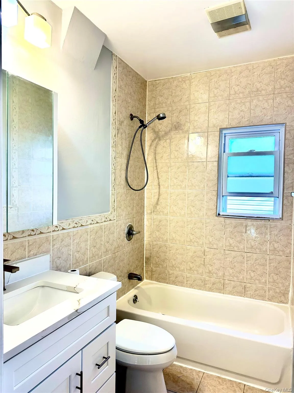 Bathroom featuring shower / washtub combination, vanity, tile walls, and tile patterned floors Bathroom featuring shower / washtub combination, vanity, tile walls, and tile patterned floors