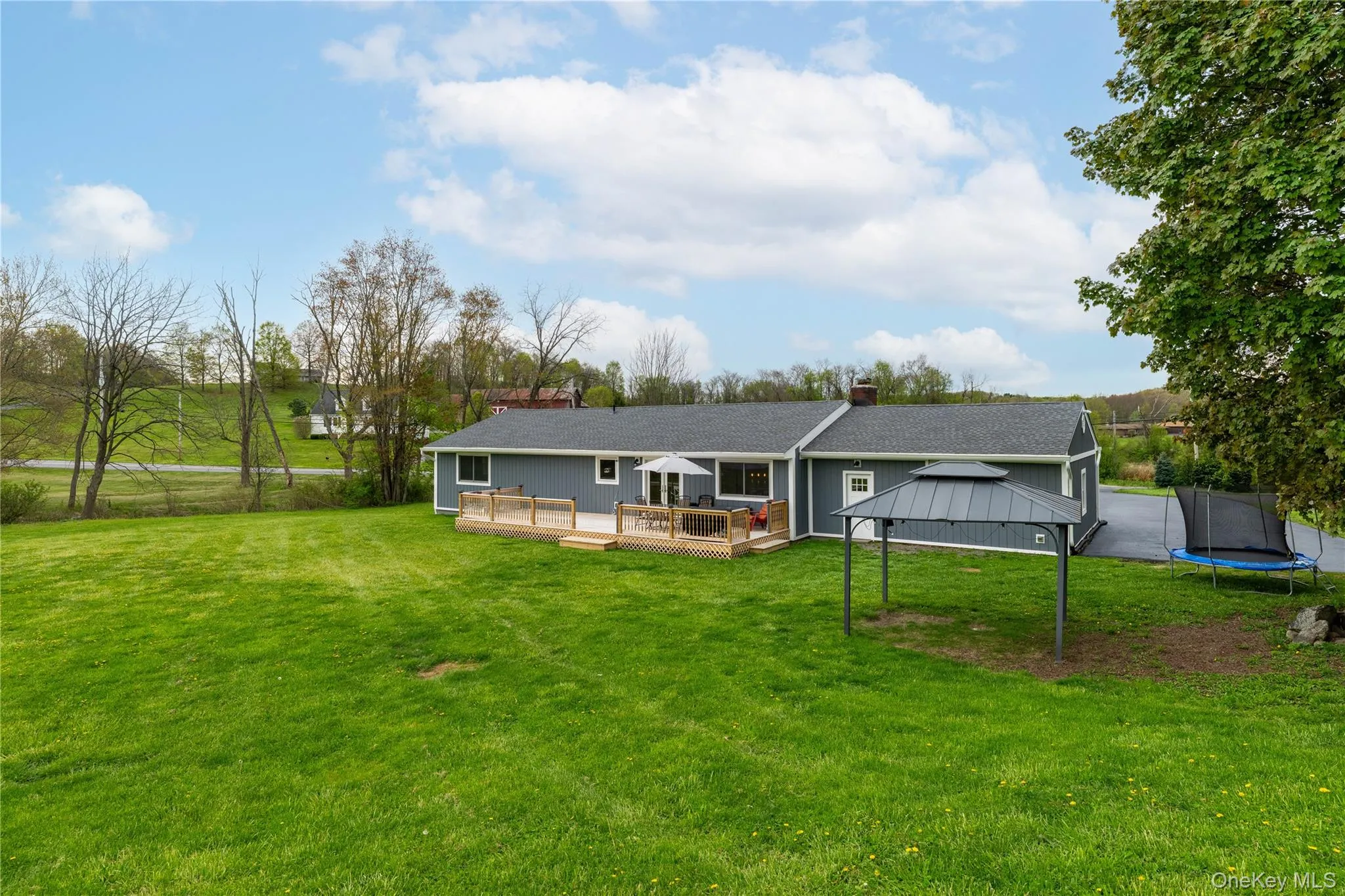 Expansive green lawn surrounds the property, featuring a wood deck Expansive green lawn surrounds the property, featuring a wood deck