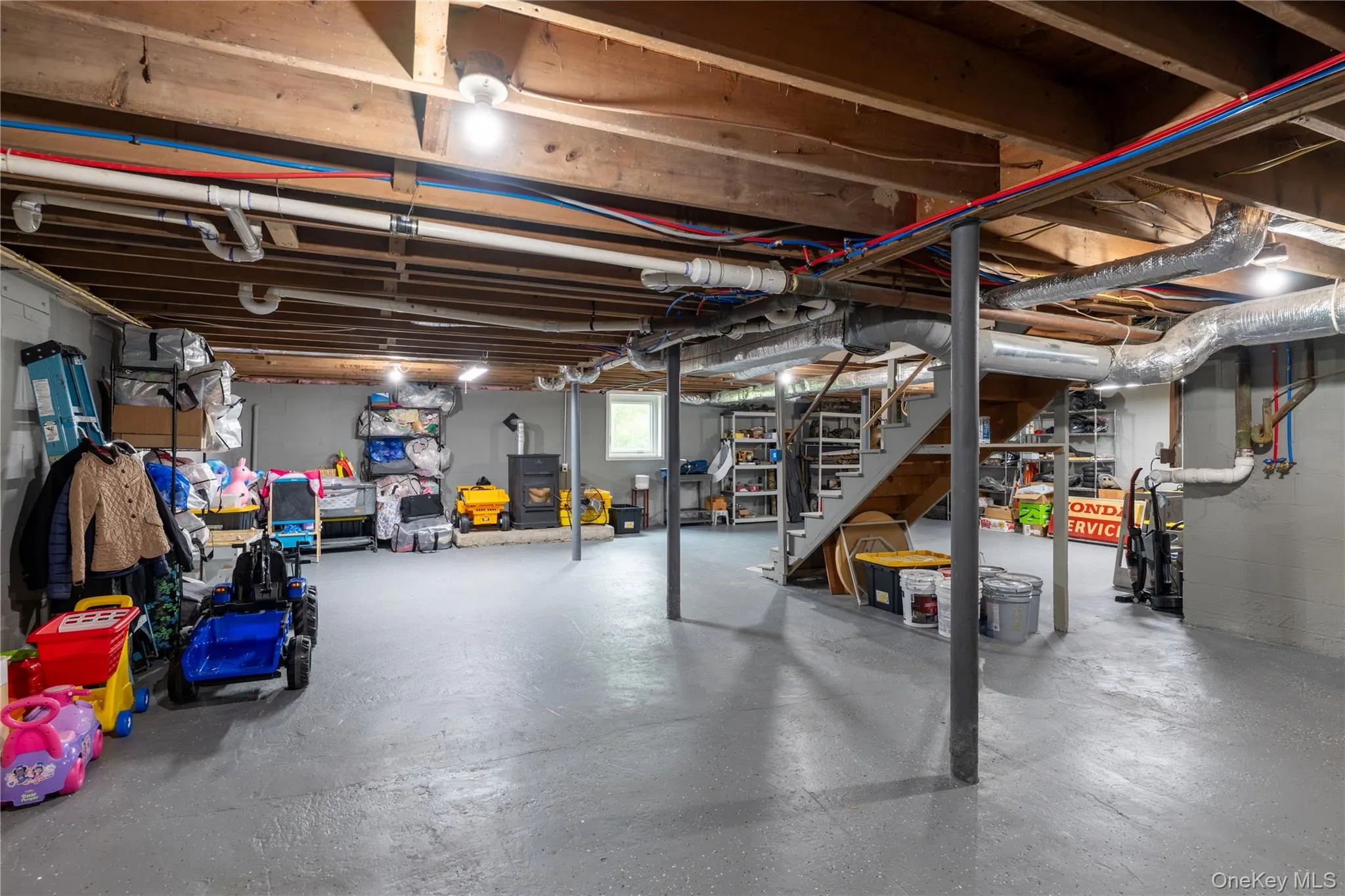 Expansive unfinished lower level with electric pellet stove, featuring exposed wood beam ceiling, epoxy flooring Expansive unfinished lower level with electric pellet stove, featuring exposed wood beam ceiling, epoxy flooring