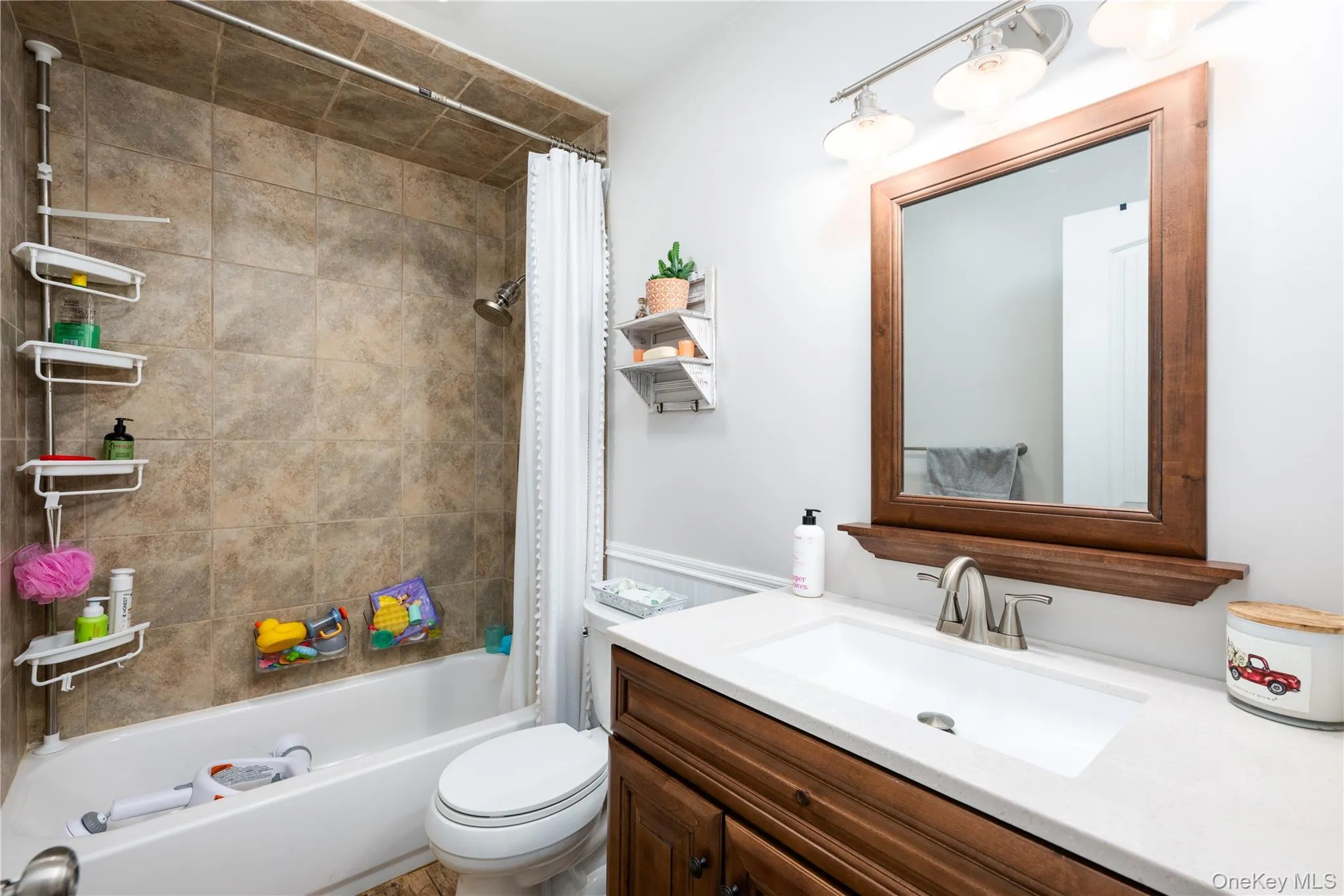 Hall Bathroom featuring a single Quartz vanity, a wood-framed mirror, and brushed nickel hardware Hall Bathroom featuring a single Quartz vanity, a wood-framed mirror, and brushed nickel hardware
