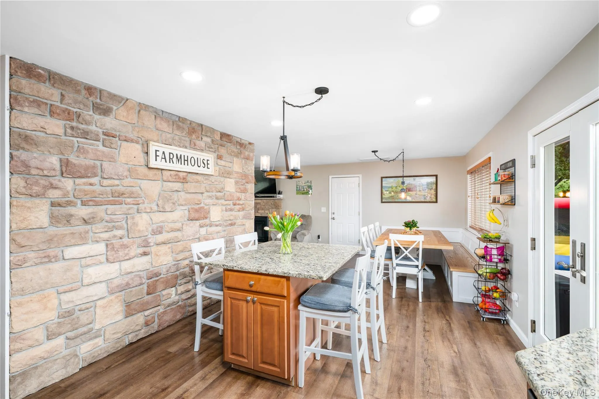 Open-concept living space with stone accent wall, and wood flooring Open-concept living space with stone accent wall, and wood flooring