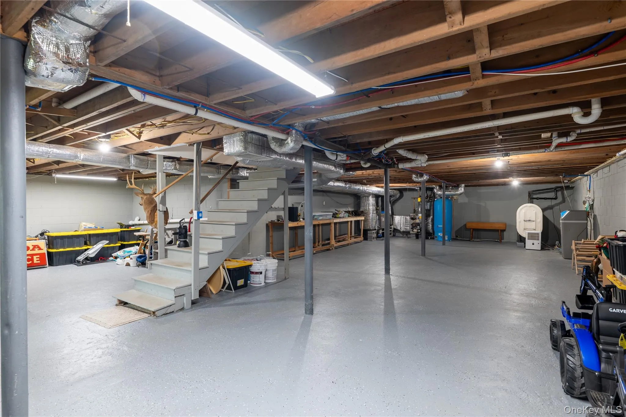 Spacious unfinished basement with epoxy flooring, exposed ceiling joists, water heater, and water softener system Spacious unfinished basement with epoxy flooring, exposed ceiling joists, water heater, and water softener system