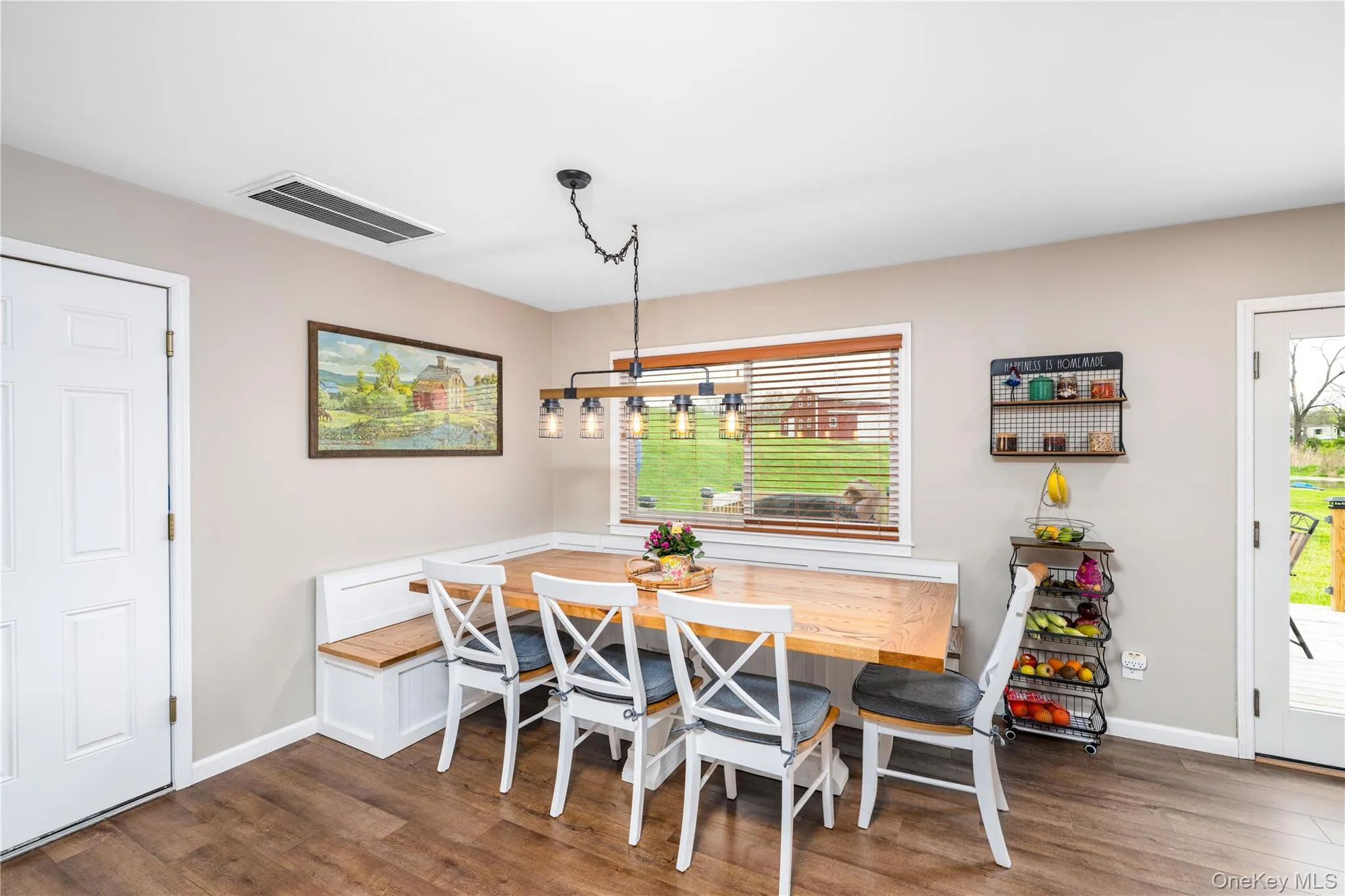 Custom built-in Dining area featuring wood flooring, a built-in bench with storage, a large window with wooden blinds, and a multi-light fixture with industrial-style caging Custom built-in Dining area featuring wood flooring, a built-in bench with storage, a large window with wooden blinds, and a multi-light fixture with industrial-style caging