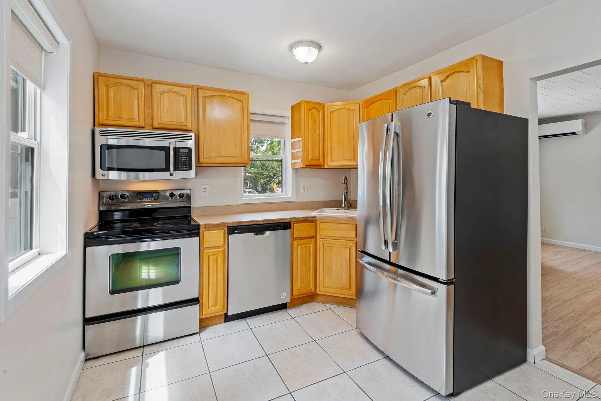 Kitchen featuring light wood cabinetry, white tile flooring, stainless steel appliances, and light-toned countertops Kitchen featuring light wood cabinetry, white tile flooring, stainless steel appliances, and light-toned countertops