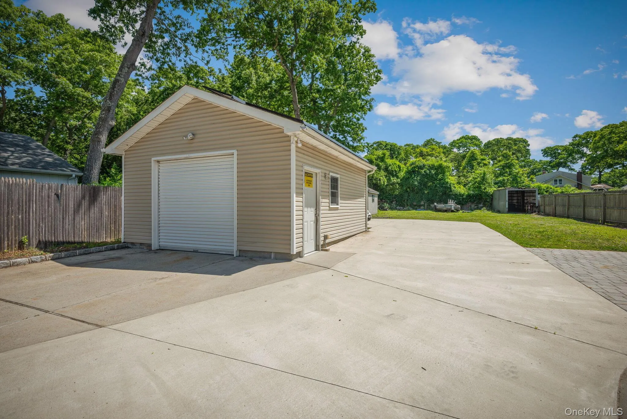 Detached one-car garage with tan siding and a white roll-up door Detached one-car garage with tan siding and a white roll-up door