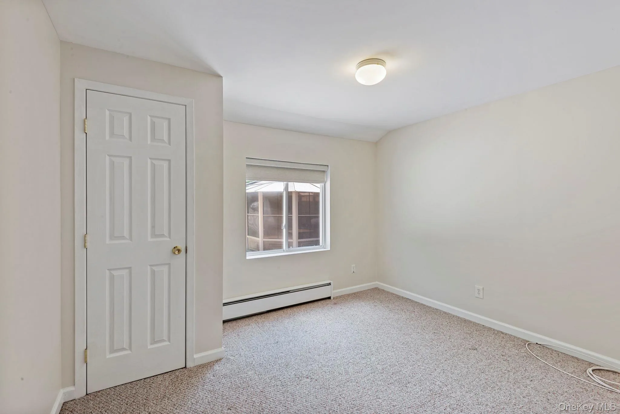 Neutral-toned room featuring a closet, window, baseboard heating, and carpet flooring Neutral-toned room featuring a closet, window, baseboard heating, and carpet flooring