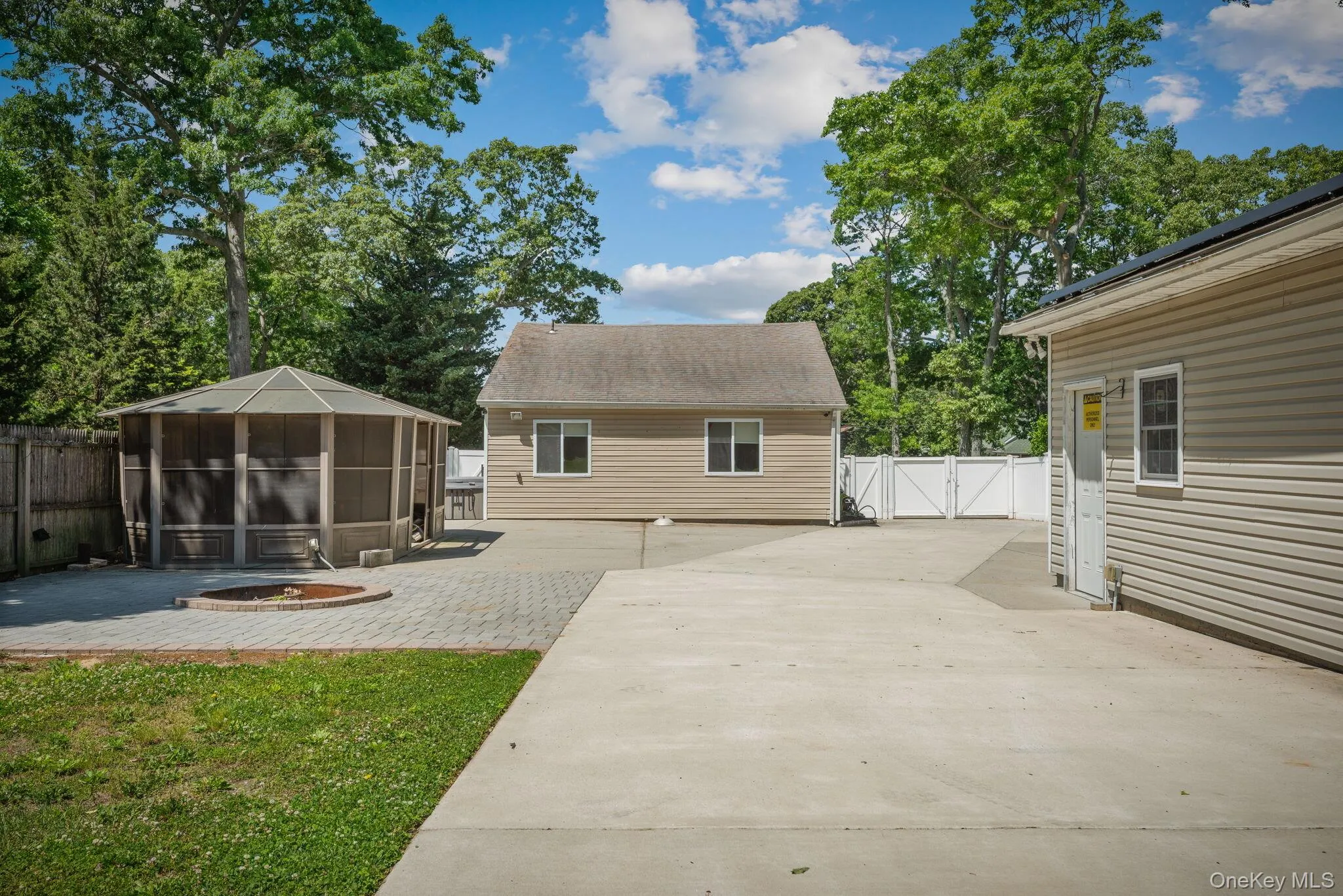 Concrete and paver patio behind house with a metal gazebo covering a BBQ area and a large screened in gazebo Concrete and paver patio behind house with a metal gazebo covering a BBQ area and a large screened in gazebo