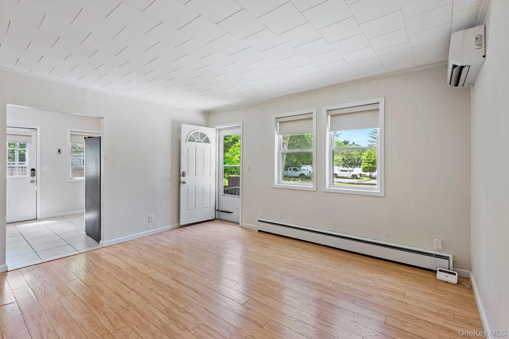 Front door leading into the living room with ductless split, ample natural light and wood flooring leading into the kitchen Front door leading into the living room with ductless split, ample natural light and wood flooring leading into the kitchen