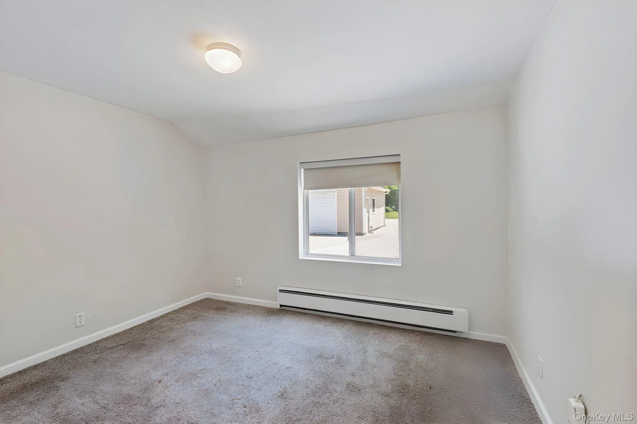 Neutral-toned room featuring a window, baseboard heating, and carpet flooring Neutral-toned room featuring a window, baseboard heating, and carpet flooring