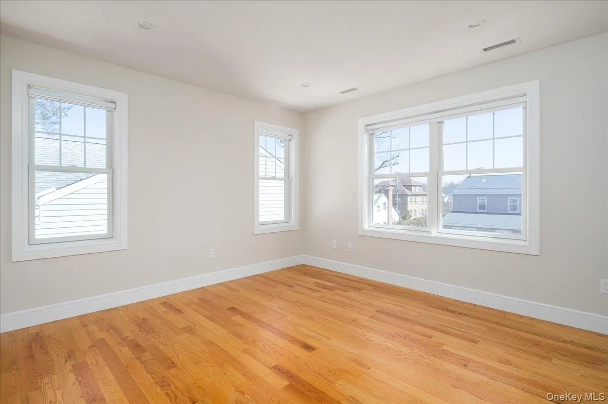 Empty room with baseboards, visible vents, and light wood-type flooring Empty room with baseboards, visible vents, and light wood-type flooring