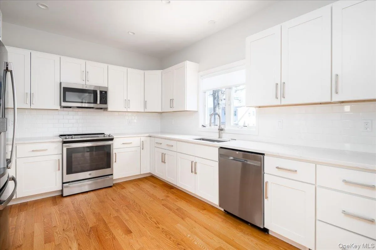 Kitchen with light countertops, a sink, stainless steel appliances, and light wood-type flooring Kitchen with light countertops, a sink, stainless steel appliances, and light wood-type flooring