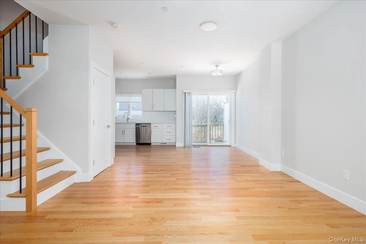Unfurnished living room with baseboards, light wood-style flooring, stairway, and a sink Unfurnished living room with baseboards, light wood-style flooring, stairway, and a sink