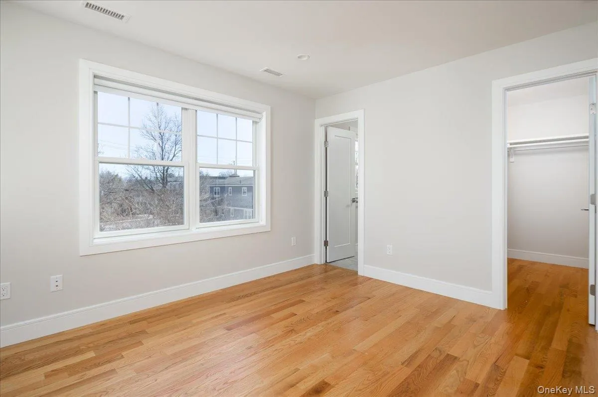 Unfurnished bedroom with a closet, a walk in closet, baseboards, visible vents, and light wood-style floors Unfurnished bedroom with a closet, a walk in closet, baseboards, visible vents, and light wood-style floors
