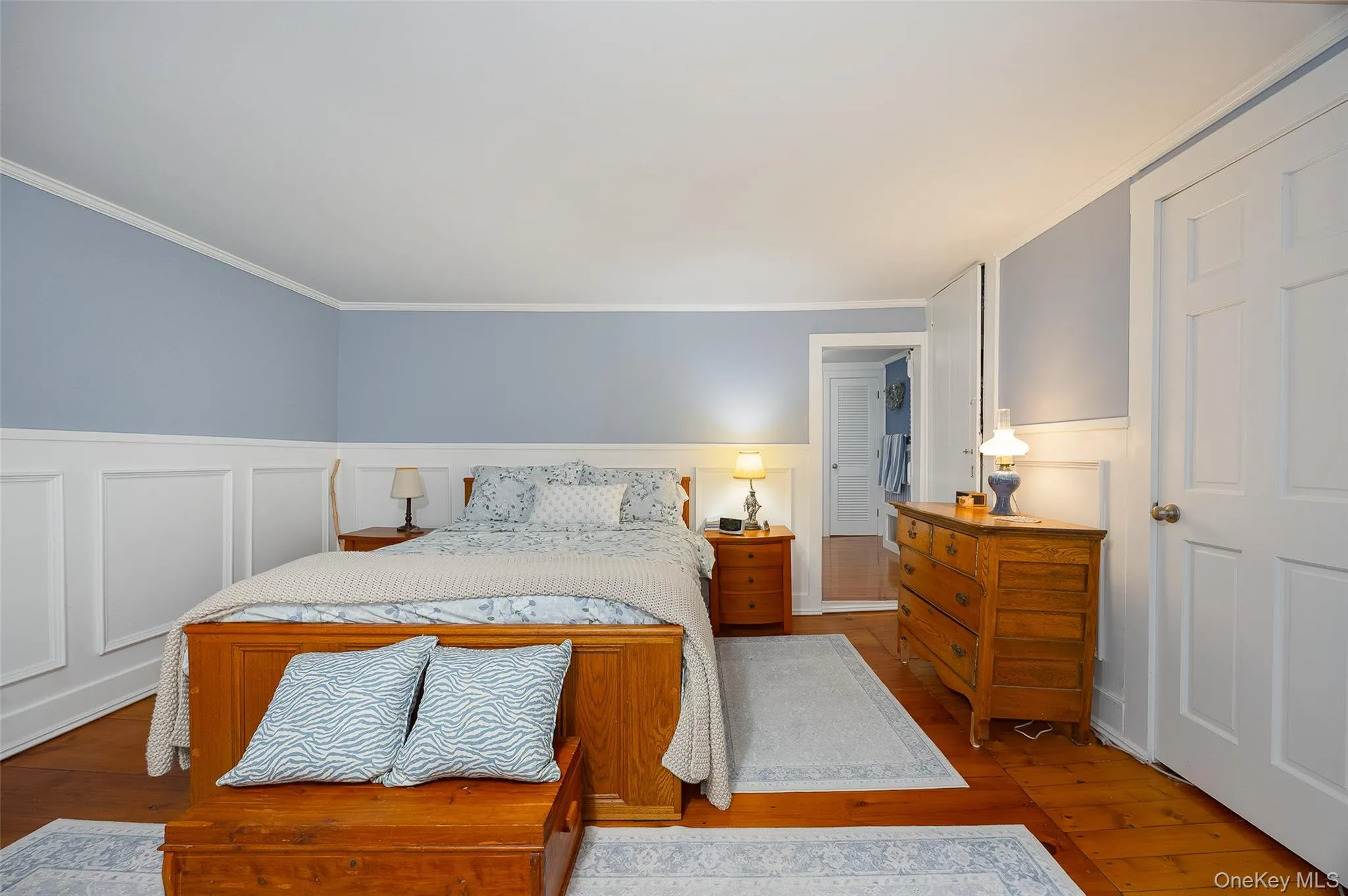 Bedroom with wainscoting, hardwood / wood-style floors, a decorative wall, and crown molding Bedroom with wainscoting, hardwood / wood-style floors, a decorative wall, and crown molding