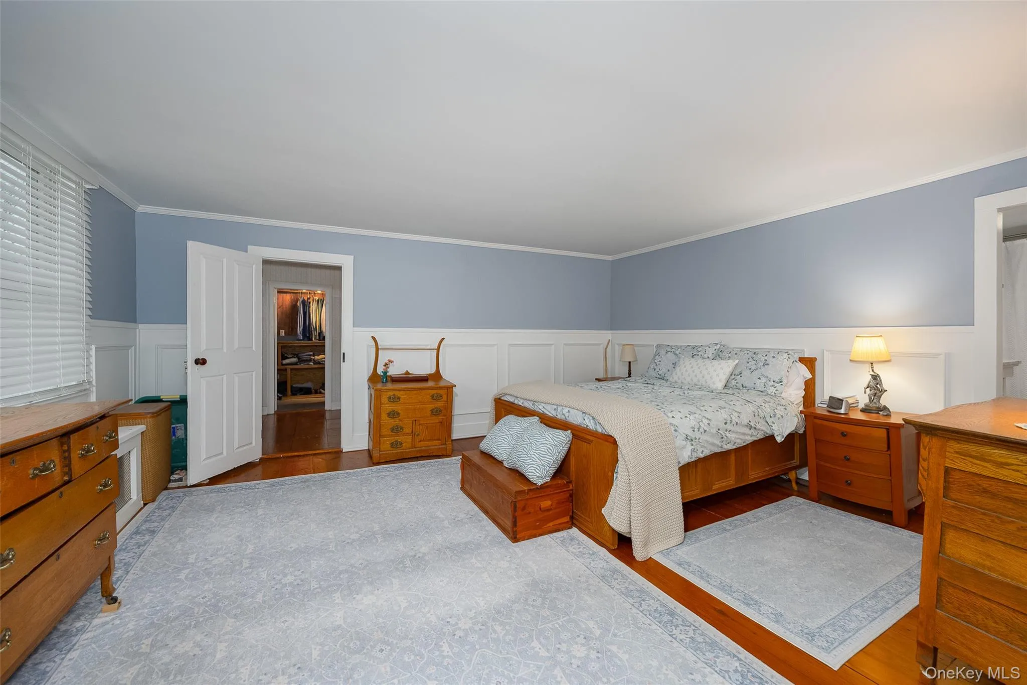 Bedroom with wood finished floors, a wainscoted wall, and ornamental molding Bedroom with wood finished floors, a wainscoted wall, and ornamental molding