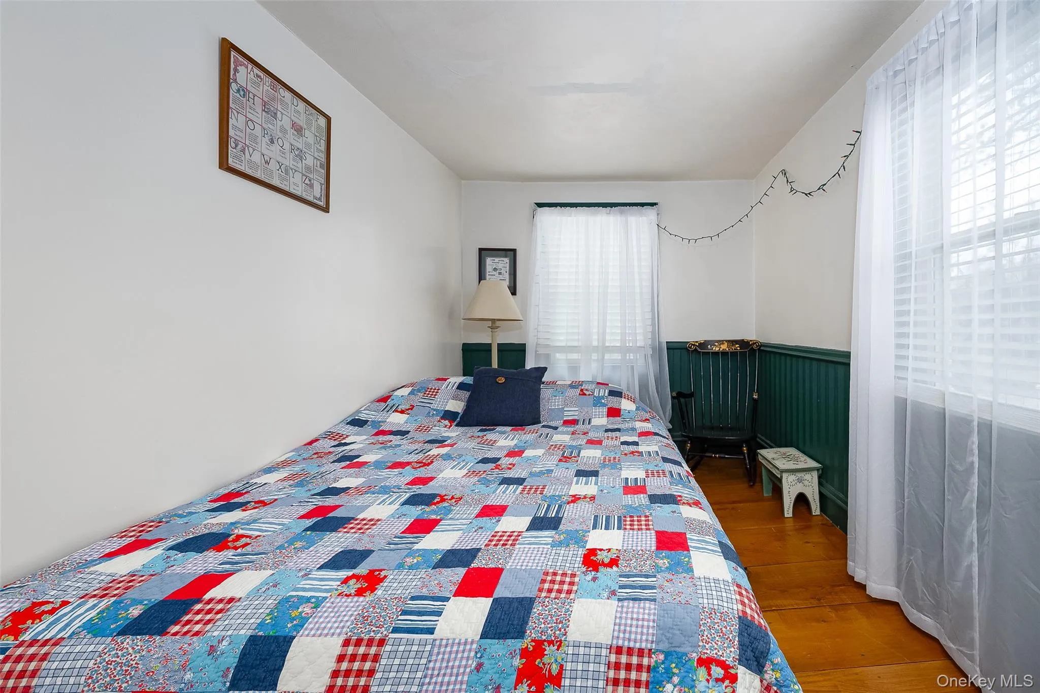 Bedroom with a wainscoted wall and wood finished floors Bedroom with a wainscoted wall and wood finished floors