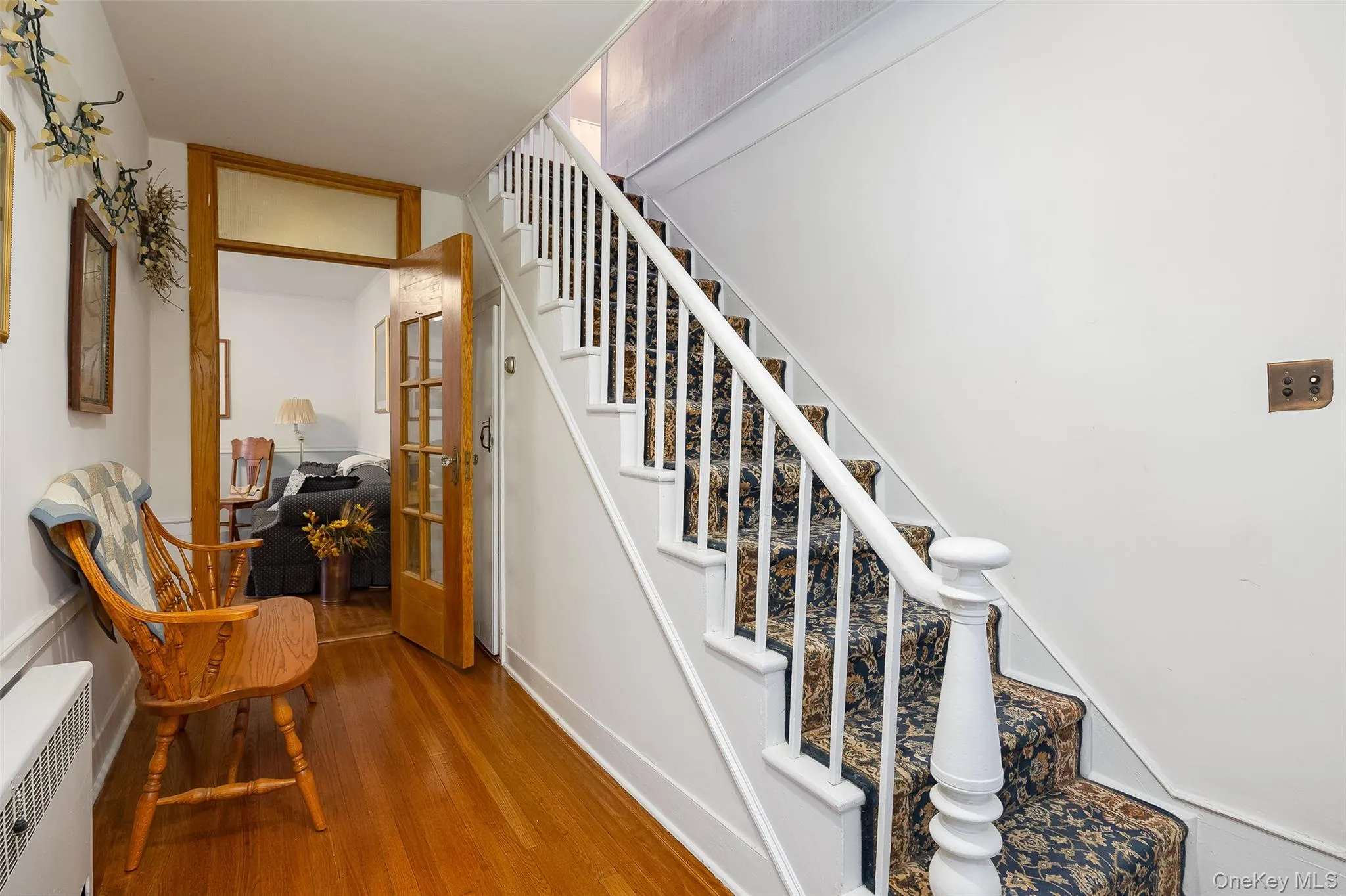 Stairs featuring wood finished floors, french doors, and radiator heating unit Stairs featuring wood finished floors, french doors, and radiator heating unit