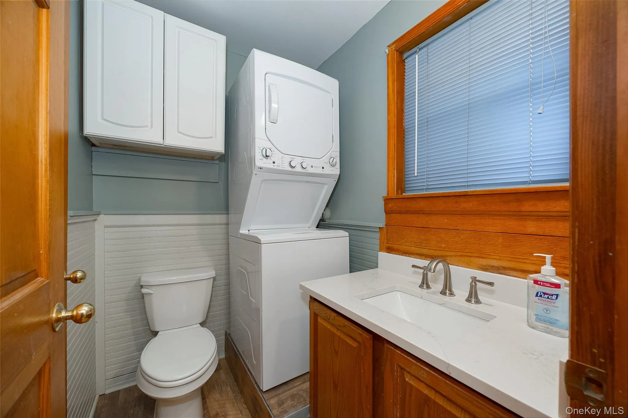 Half bath featuring vanity, stacked washer / dryer wainscoting, and dark wood-style floors #2 Half bath featuring vanity, stacked washer / dryer wainscoting, and dark wood-style floors #2
