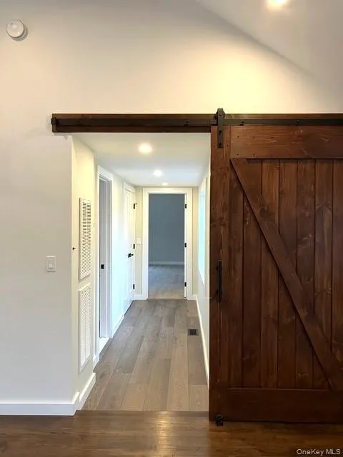 A Barn Door Off Of The Great Room Leads To A Hallway Offering Double Doors To A Full Sized Samsung Washer & Dryer, Beautiful Plank Flooring & Into The Primary Bedroom & Primary Bathroom. A Barn Door Off Of The Great Room Leads To A Hallway Offering Double Doors To A Full Sized Samsung Washer & Dryer, Beautiful Plank Flooring & Into The Primary Bedroom & Primary Bathroom.