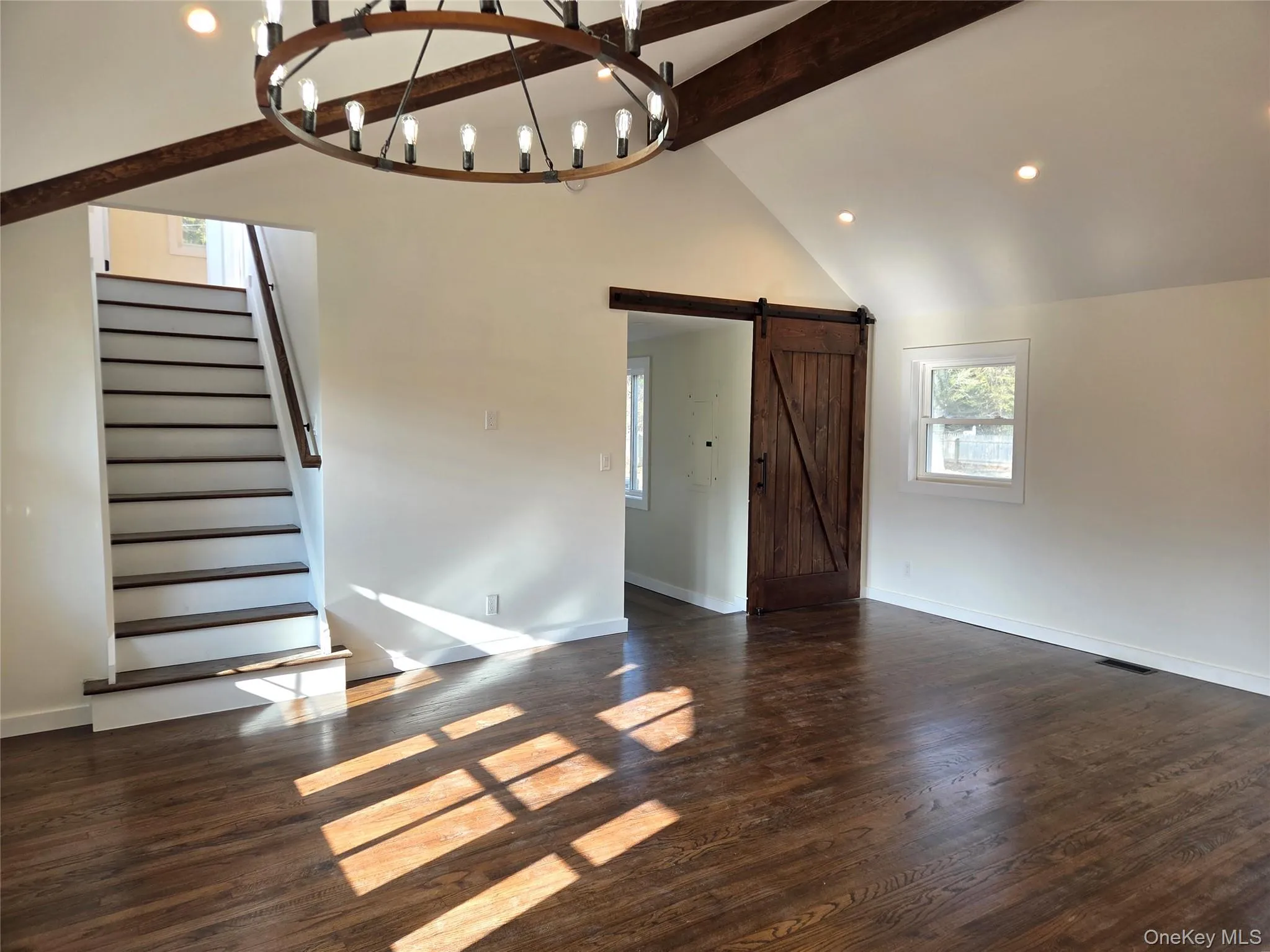 Another View Of The Great Room Offering Stunning Beamed Ceilings, Hardwood Floors, Recessed Lighting, Chandelier, A Beautiful Stairway To The Second Level & A Barn Style Door To The Primary Bedroom. Another View Of The Great Room Offering Stunning Beamed Ceilings, Hardwood Floors, Recessed Lighting, Chandelier, A Beautiful Stairway To The Second Level & A Barn Style Door To The Primary Bedroom.
