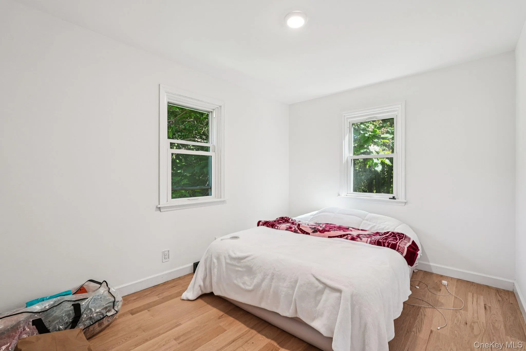 Bedroom with multiple windows and wood-like finished floors Bedroom with multiple windows and wood-like finished floors