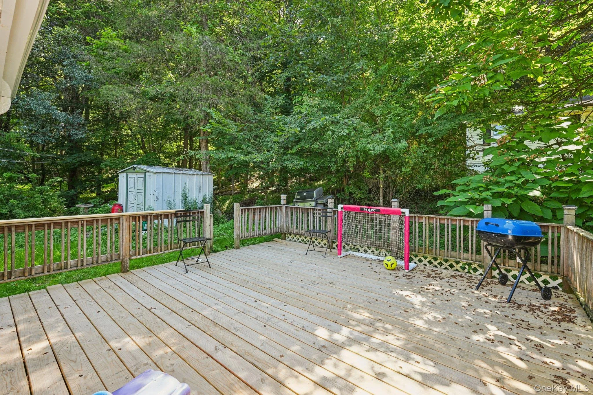 Wooden deck featuring a shed and area for grilling Wooden deck featuring a shed and area for grilling