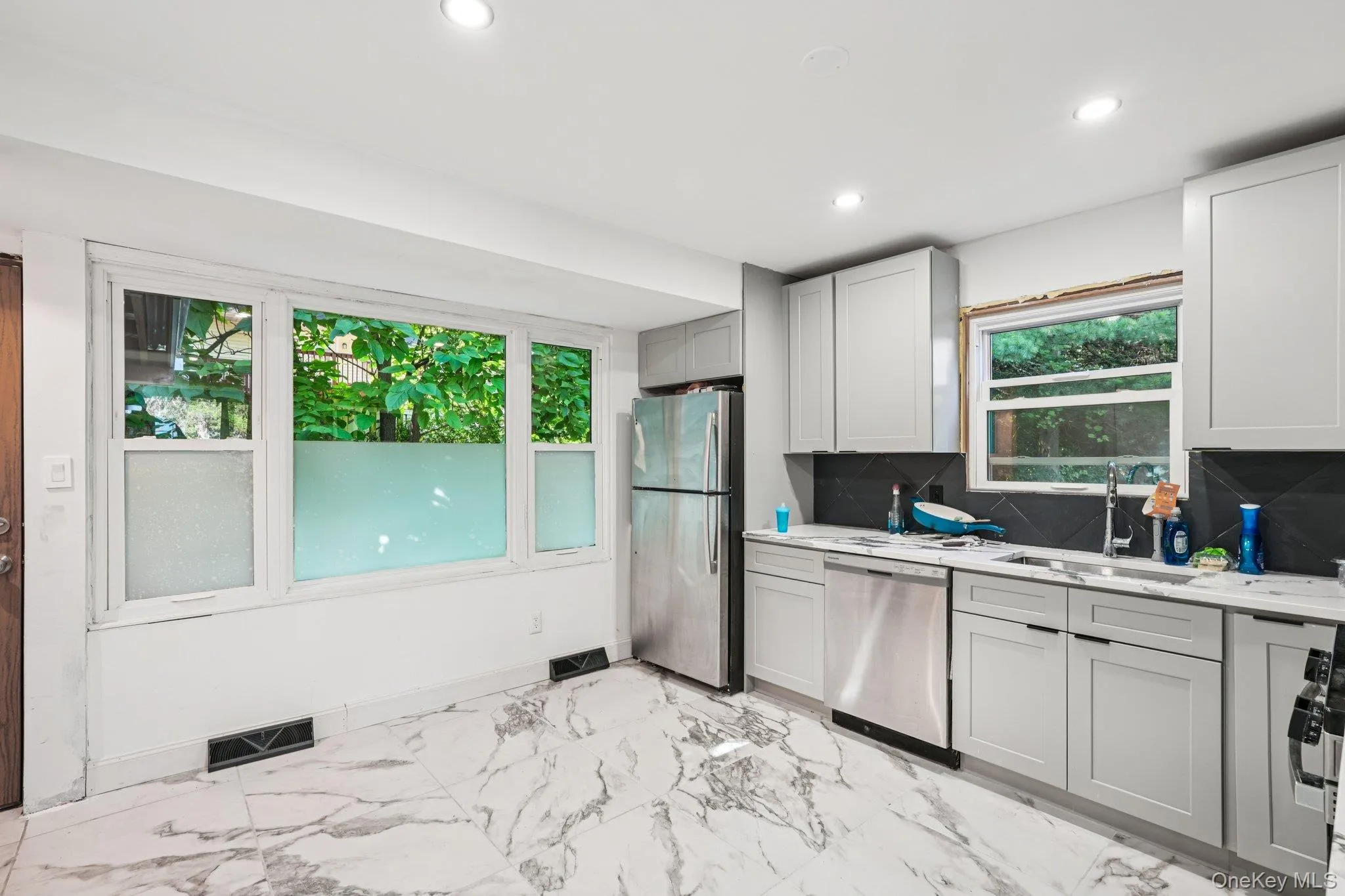 Kitchen featuring appliances with stainless steel finishes, recessed lighting, light marbled flooring, backsplash, and gray cabinetry Kitchen featuring appliances with stainless steel finishes, recessed lighting, light marbled flooring, backsplash, and gray cabinetry