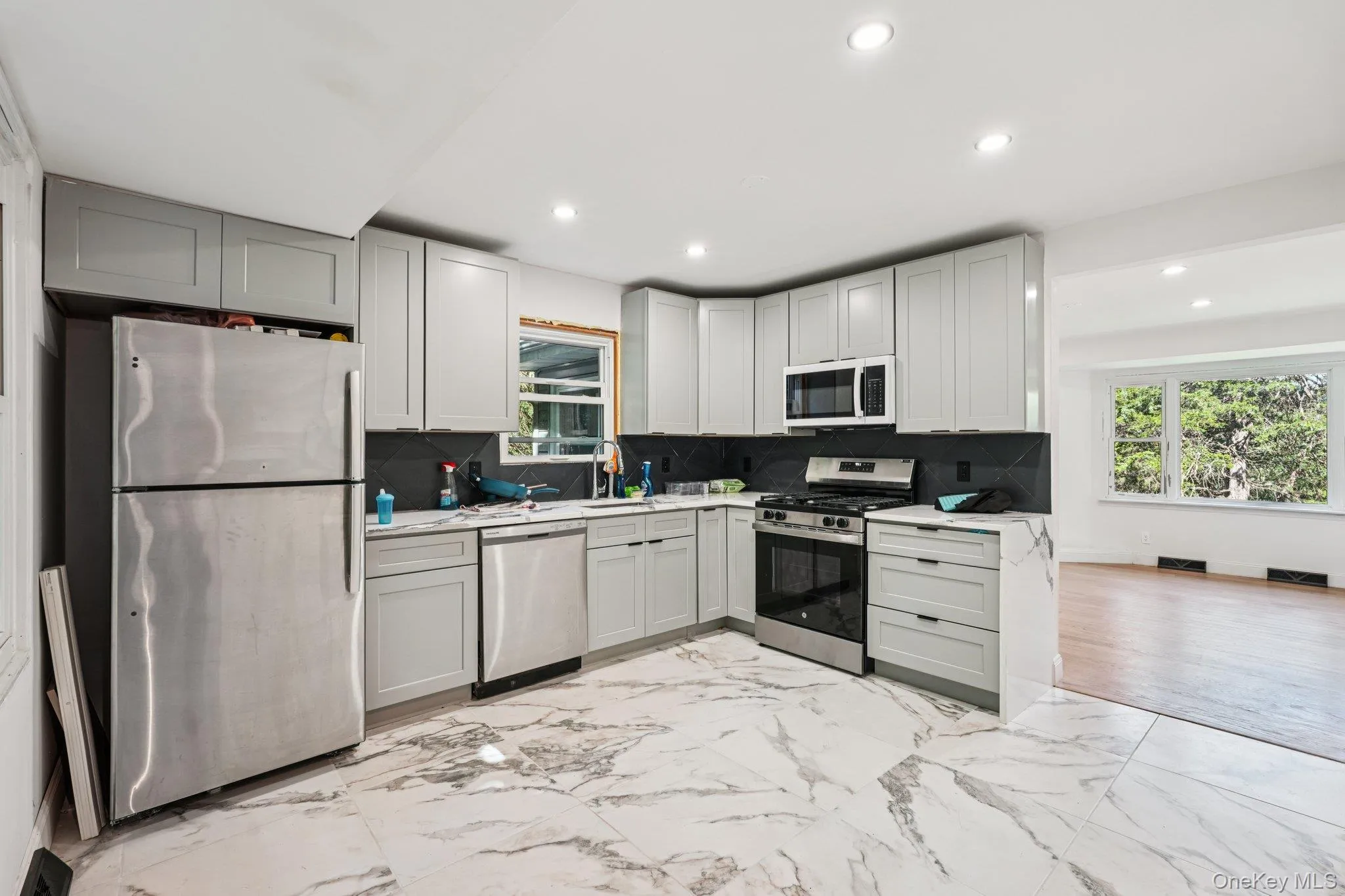 Kitchen featuring stainless steel appliances, light countertops, recessed lighting, light marbled flooring, and tasteful backsplash Kitchen featuring stainless steel appliances, light countertops, recessed lighting, light marbled flooring, and tasteful backsplash