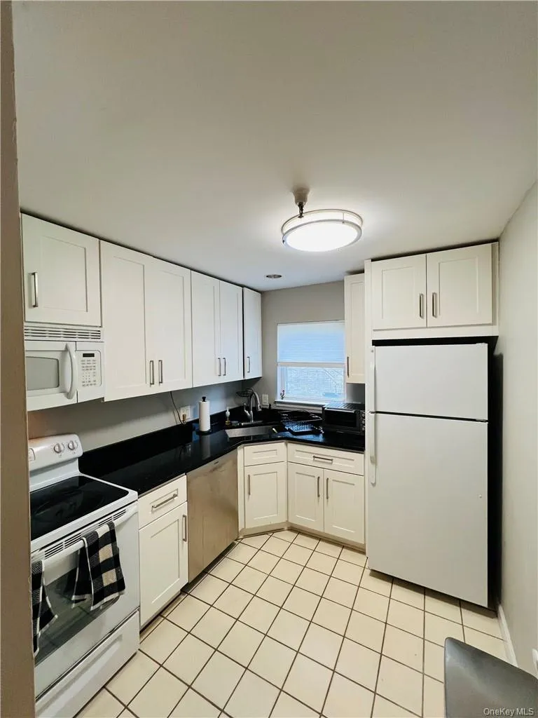 Kitchen with white cabinetry, white appliances, and light tile patterned floors Kitchen with white cabinetry, white appliances, and light tile patterned floors