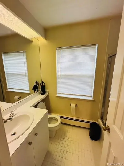 Bathroom featuring toilet, tile patterned floors, a baseboard radiator, and vanity Bathroom featuring toilet, tile patterned floors, a baseboard radiator, and vanity