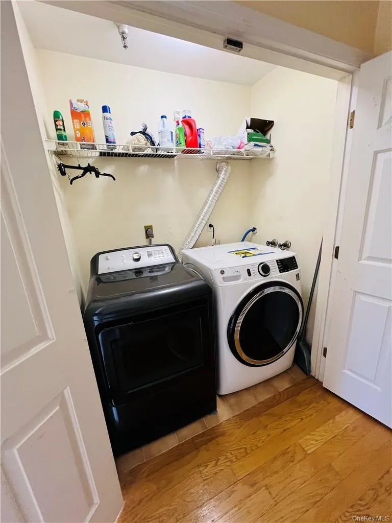 Laundry room with full size washing machine and dryer and light wood-type flooring Laundry room with full size washing machine and dryer and light wood-type flooring
