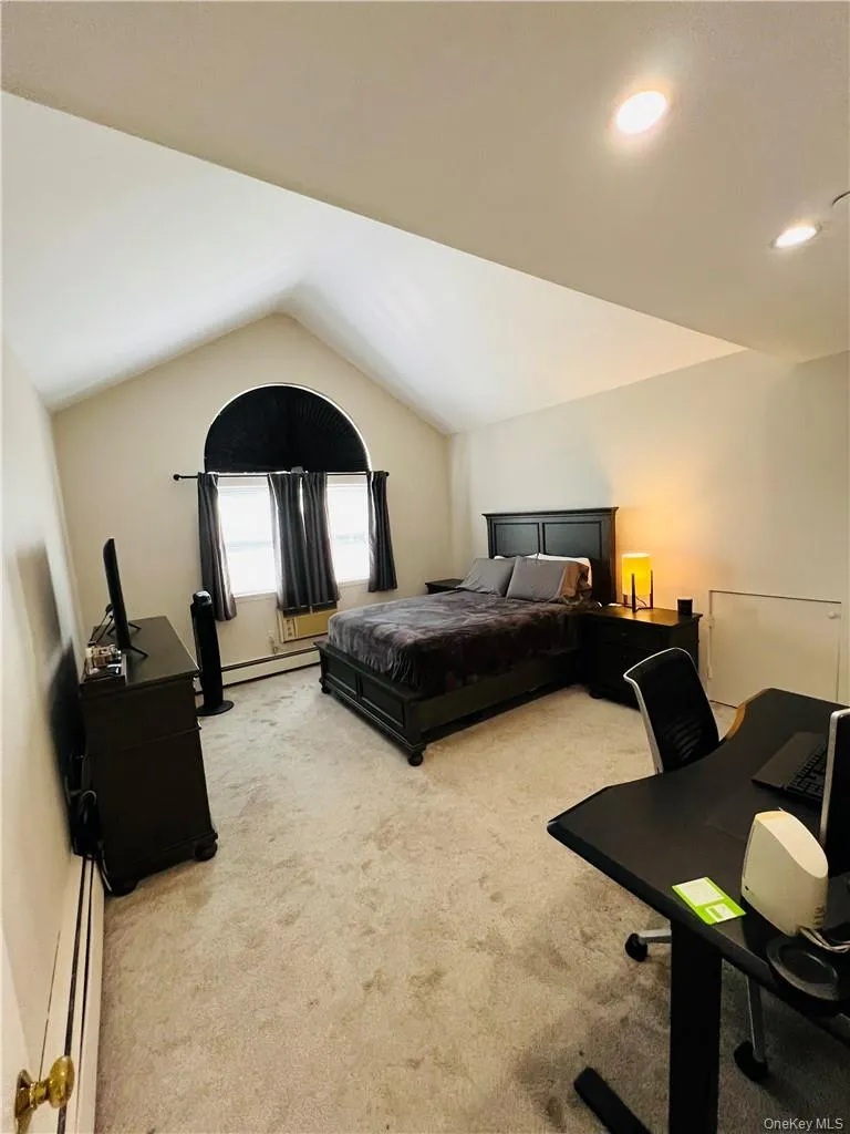 Large primary bedroom featuring baseboard heating and vaulted ceiling Large primary bedroom featuring baseboard heating and vaulted ceiling
