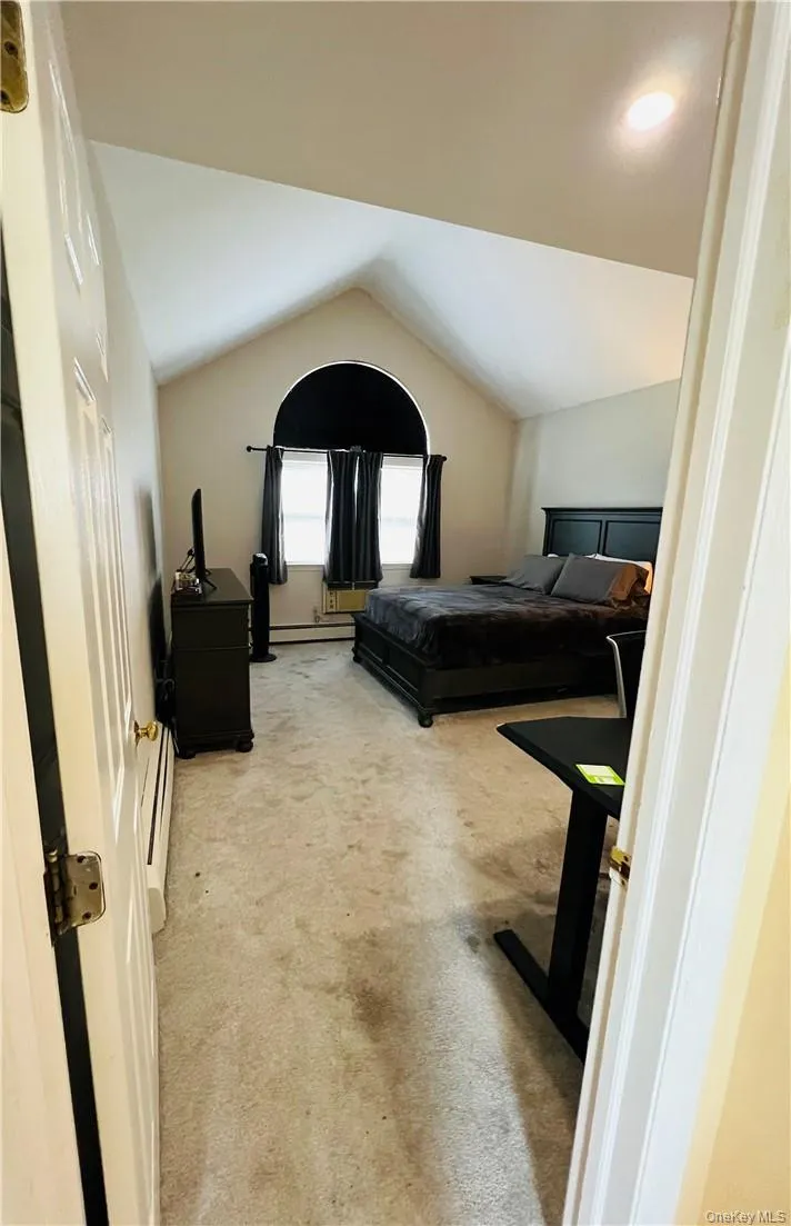 Bedroom with lofted ceiling, baseboard heating, and carpet Bedroom with lofted ceiling, baseboard heating, and carpet