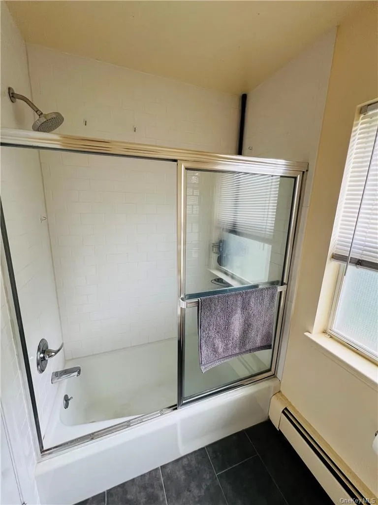 Bathroom featuring a wealth of natural light, a baseboard heating unit, and tile patterned floors Bathroom featuring a wealth of natural light, a baseboard heating unit, and tile patterned floors