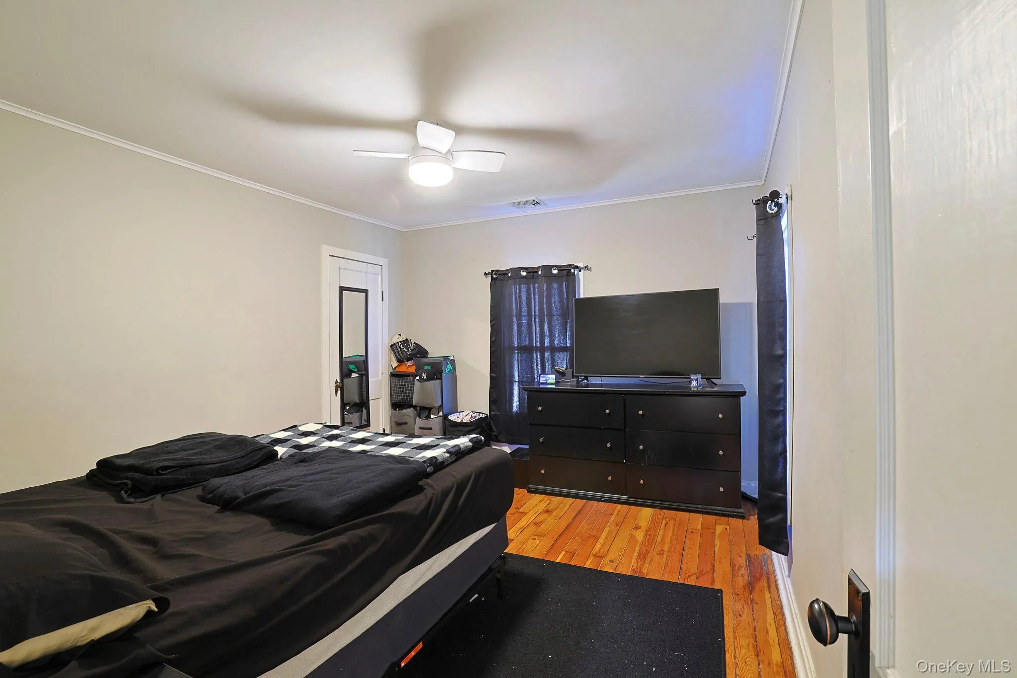Bedroom with a ceiling fan, visible vents, light wood-style floors, and crown molding Bedroom with a ceiling fan, visible vents, light wood-style floors, and crown molding