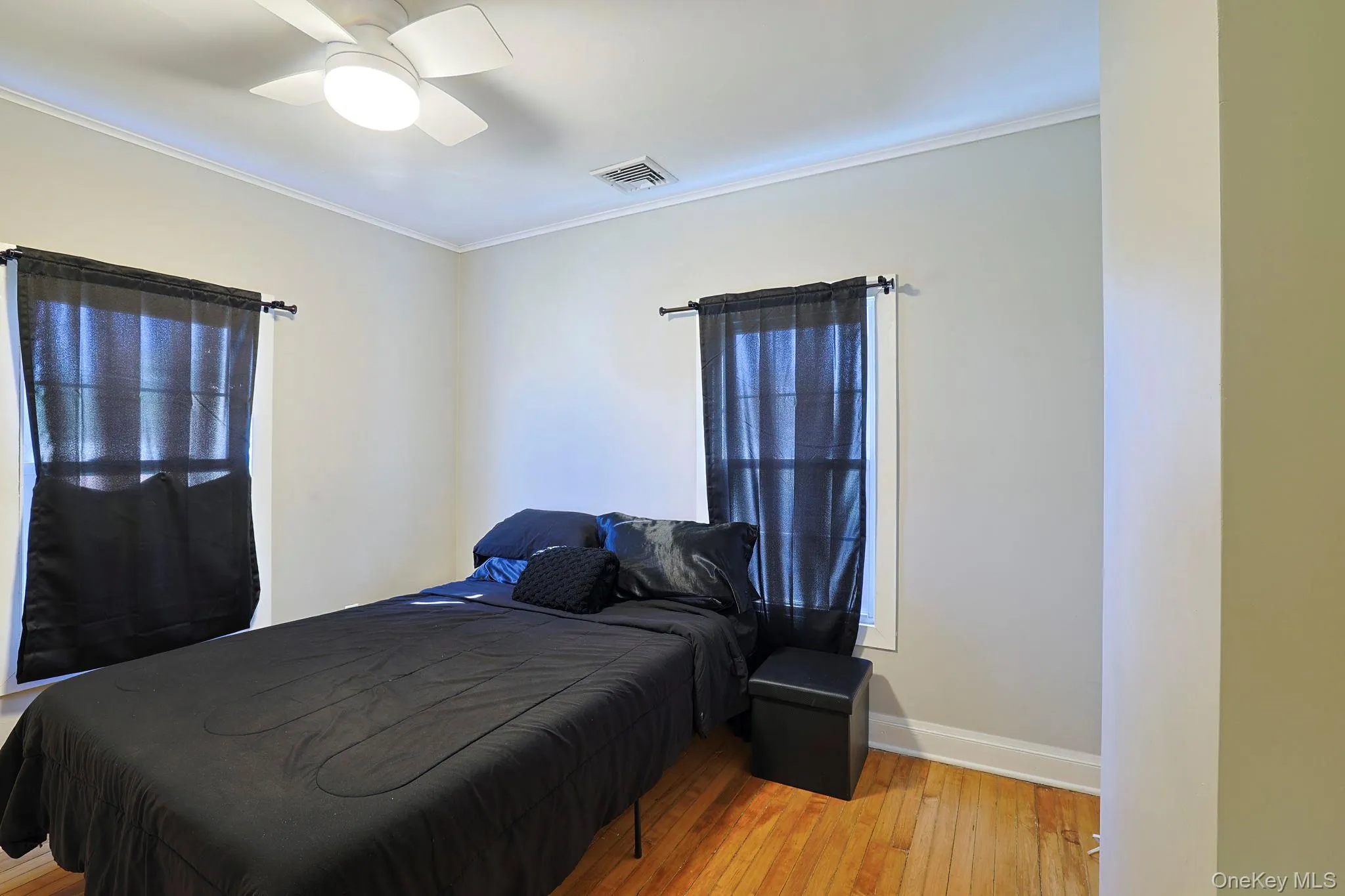 Bedroom with visible vents, a ceiling fan, ornamental molding, baseboards, and hardwood / wood-style flooring Bedroom with visible vents, a ceiling fan, ornamental molding, baseboards, and hardwood / wood-style flooring
