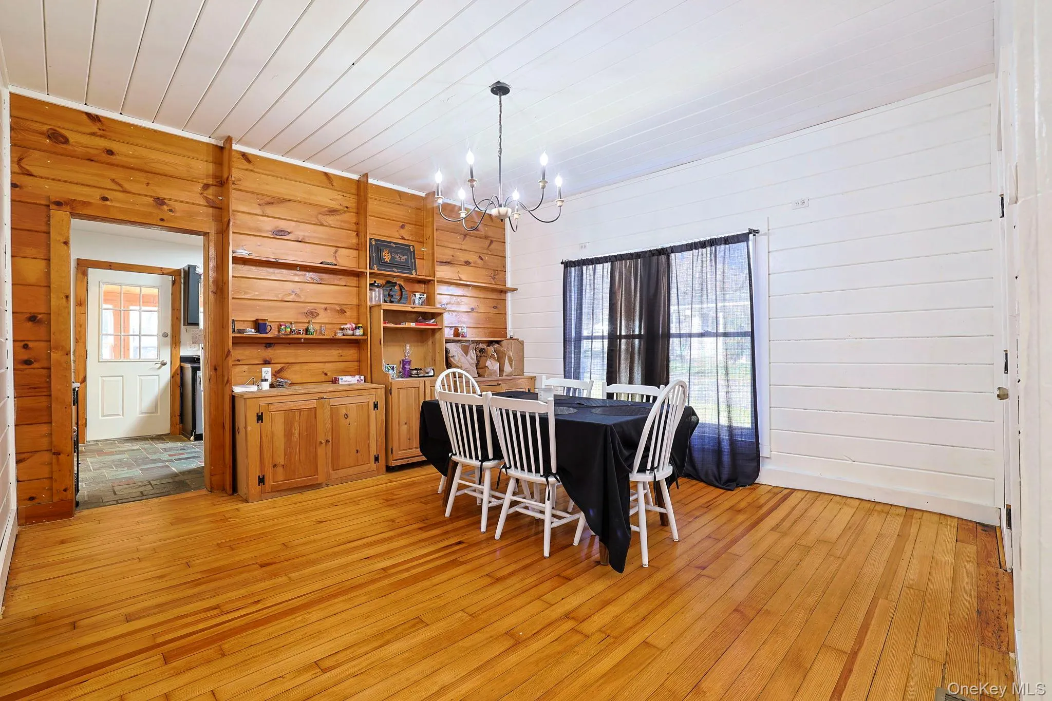 Dining space featuring wood ceiling, an inviting chandelier, wood walls, and light wood-type flooring Dining space featuring wood ceiling, an inviting chandelier, wood walls, and light wood-type flooring