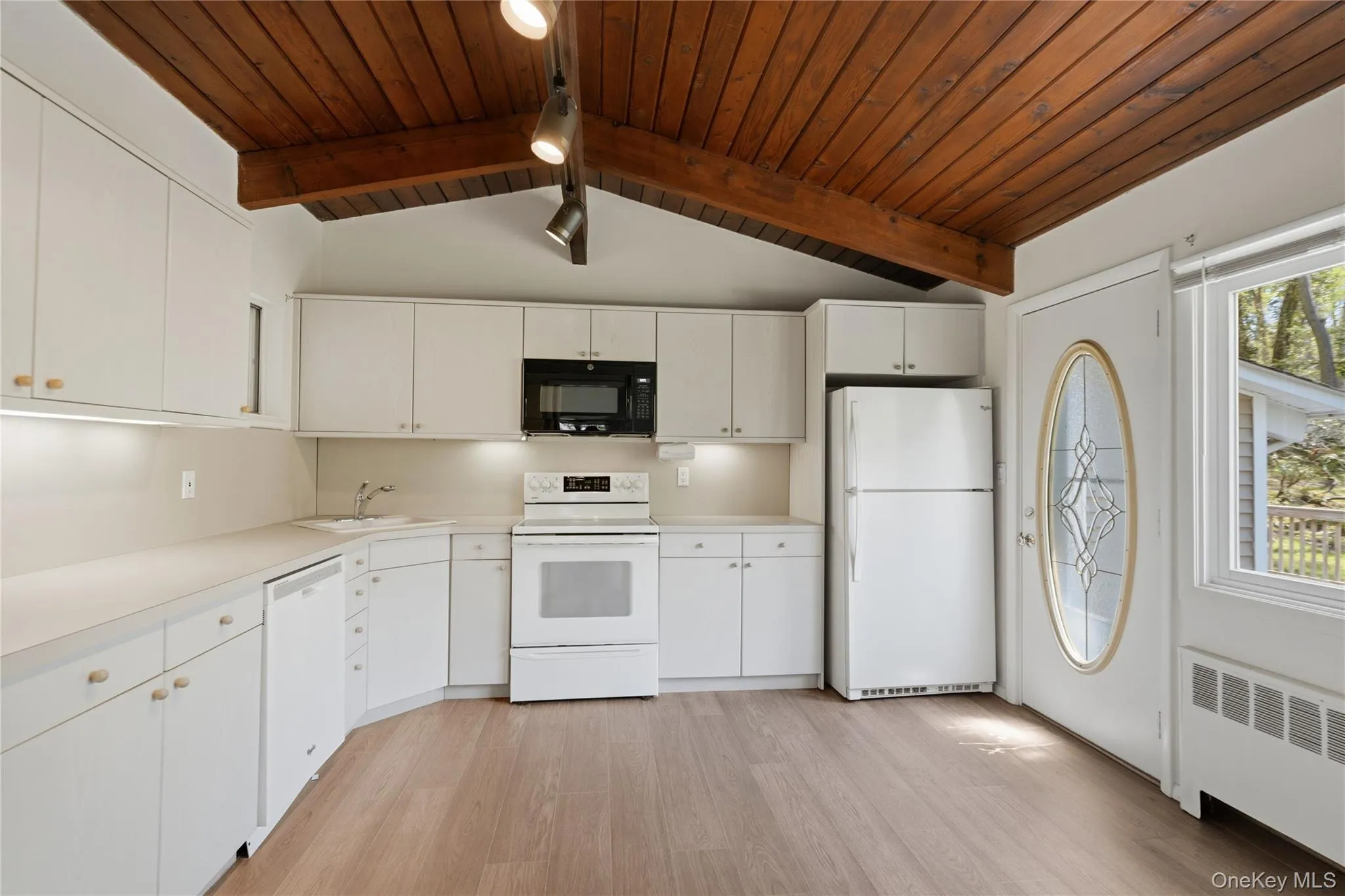 Kitchen featuring vaulted wood-plank ceiling with exposed beam, track lighting, light wood-finish flooring and neutral cabinetry Kitchen featuring vaulted wood-plank ceiling with exposed beam, track lighting, light wood-finish flooring and neutral cabinetry