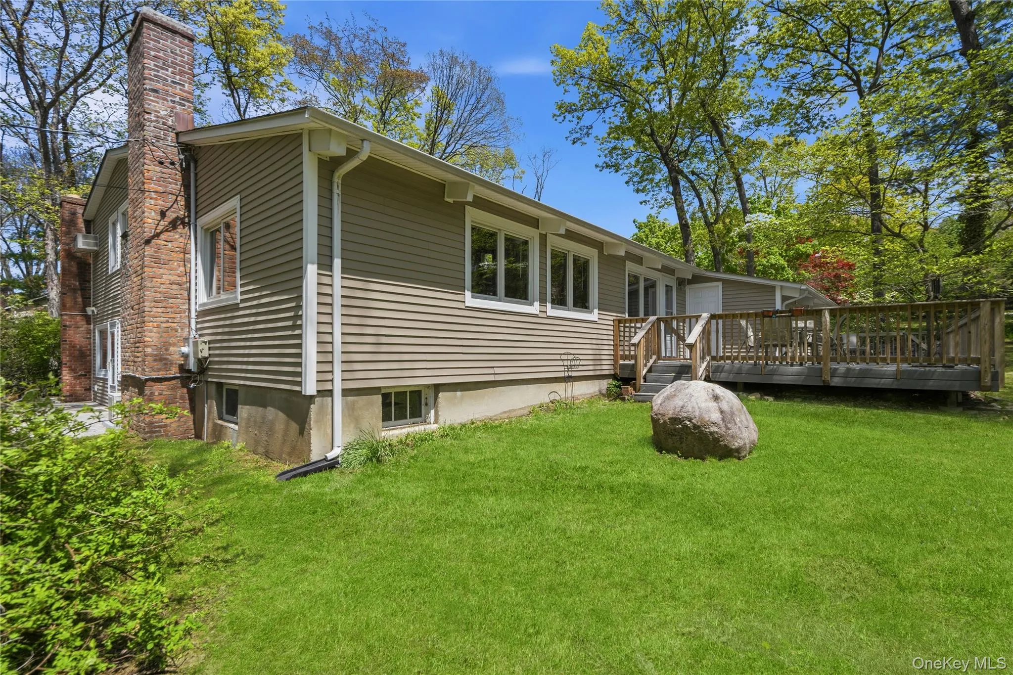 Rear exterior showcasing horizontal siding and a large wooden deck Rear exterior showcasing horizontal siding and a large wooden deck