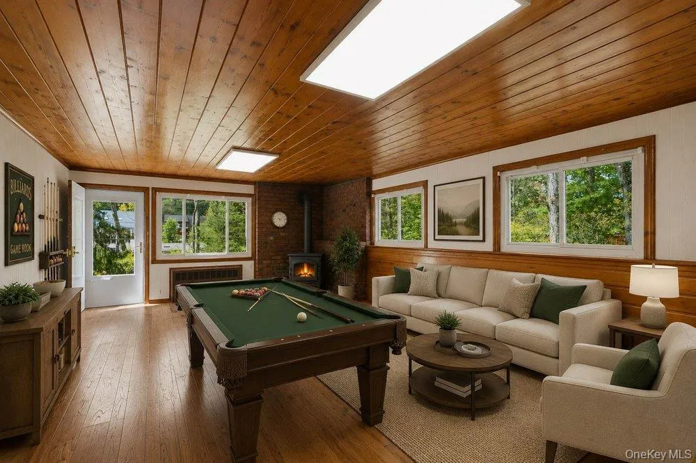 Spacious recreation room featuring wood-finish flooring, a wood plank ceiling, and multiple windows Spacious recreation room featuring wood-finish flooring, a wood plank ceiling, and multiple windows