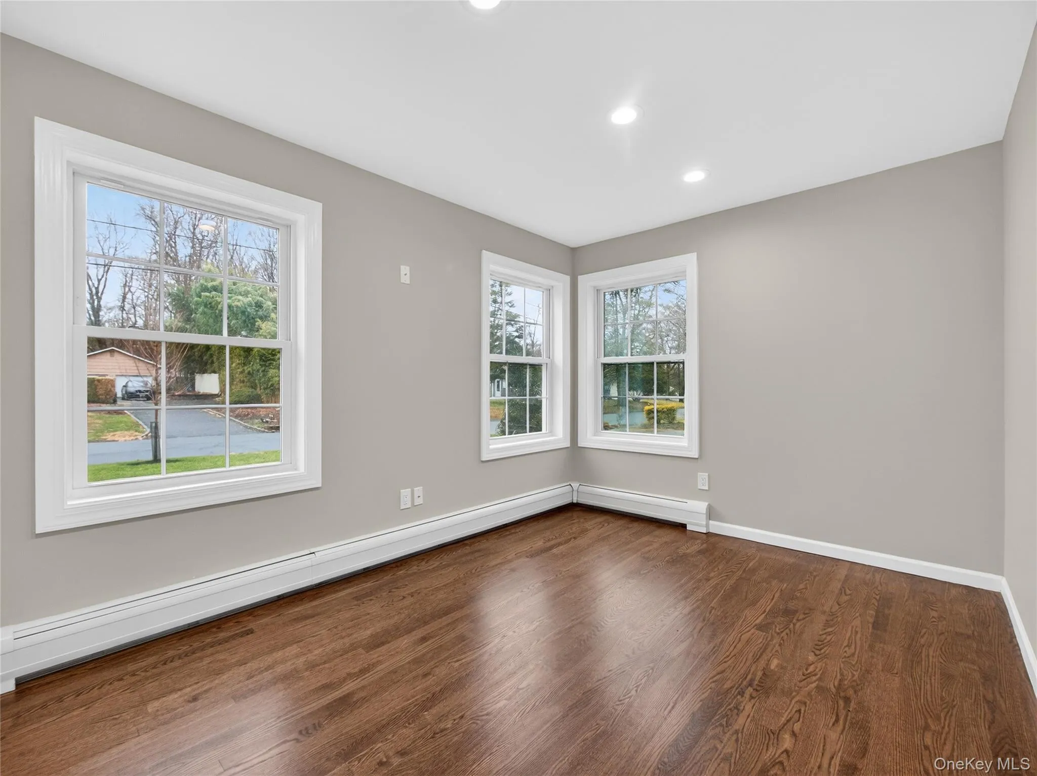 Empty room featuring a baseboard radiator, dark wood-type flooring, and recessed lighting Empty room featuring a baseboard radiator, dark wood-type flooring, and recessed lighting